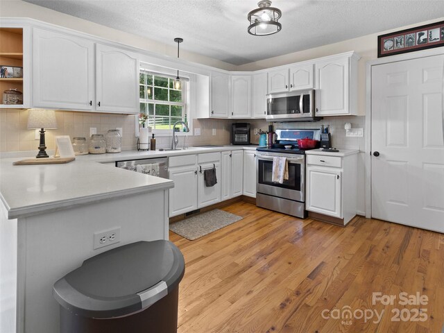 3906 Brickfield St, Hickory, NC 28602 - kitchen featuring stainless steel appliances, a peninsula, white cabinetry, decorative backsplash, and light countertops