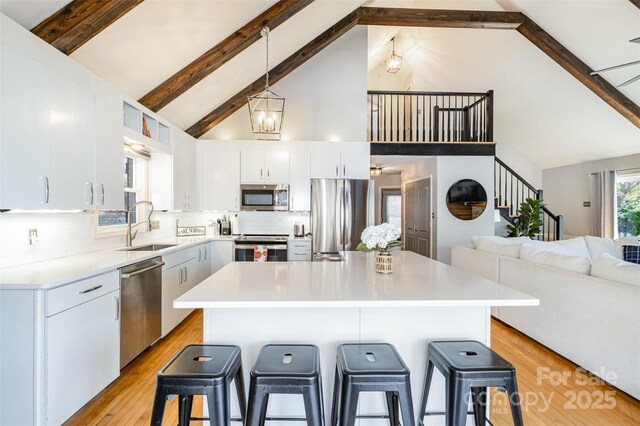 353 Whippoorwill Rd, Mooresville, NC 28117 - kitchen with stainless steel appliances, high vaulted ceiling, a breakfast bar area, beamed ceiling, and light countertops