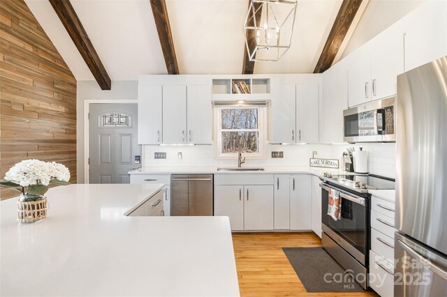 353 Whippoorwill Rd, Mooresville, NC 28117 - kitchen with stainless steel appliances, wooden walls, tasteful backsplash, light countertops, and light wood-type flooring