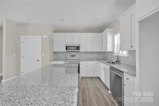 222 Elm St, Mocksville, NC 27028 - kitchen with appliances with stainless steel finishes, white cabinetry, light stone countertops, and decorative backsplash