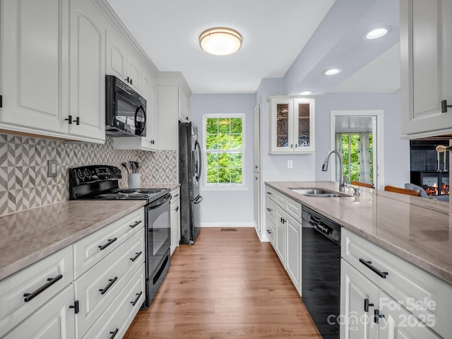 198 Sugarbush Pt, Lake Lure, NC 28746 - kitchen with black appliances, light wood-type flooring, tasteful backsplash, white cabinetry, and light stone countertops