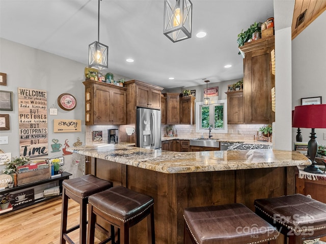 3094 Connestee Trl, Brevard, NC 28712 - kitchen with appliances with stainless steel finishes, a peninsula, tasteful backsplash, light stone counters, and light wood-style floors