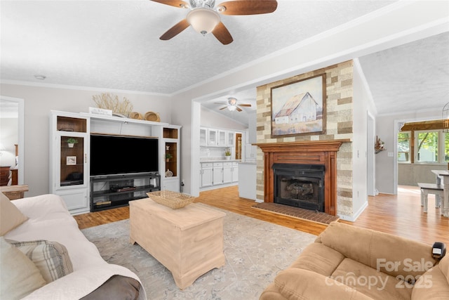 4534 Pebblebrook Cir SW, Concord, NC 28027 - living room with a ceiling fan, light wood-style flooring, a textured ceiling, a fireplace with raised hearth, and ornamental molding