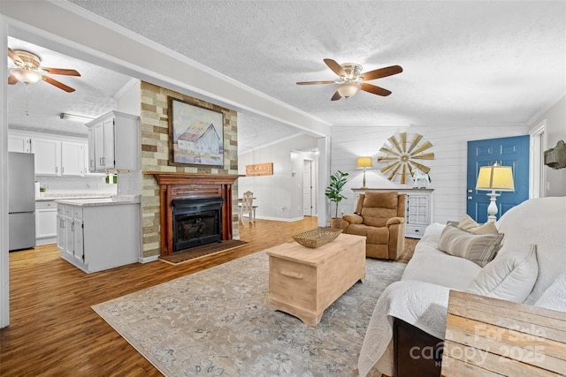 4534 Pebblebrook Cir SW, Concord, NC 28027 - living area with ceiling fan, a textured ceiling, a large fireplace, light wood-type flooring, and ornamental molding