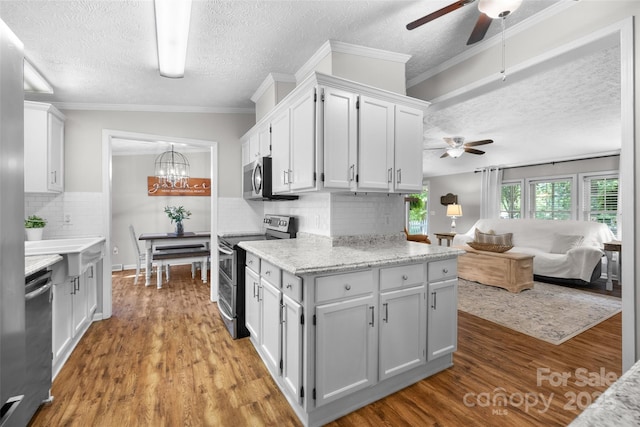 4534 Pebblebrook Cir SW, Concord, NC 28027 - kitchen with stainless steel appliances, a ceiling fan, a textured ceiling, tasteful backsplash, and a chandelier