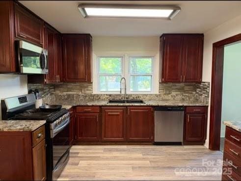 148 Barium Ln, Statesville, NC 28677 - kitchen featuring appliances with stainless steel finishes, light wood-style flooring, decorative backsplash, light stone counters, and reddish brown cabinets
