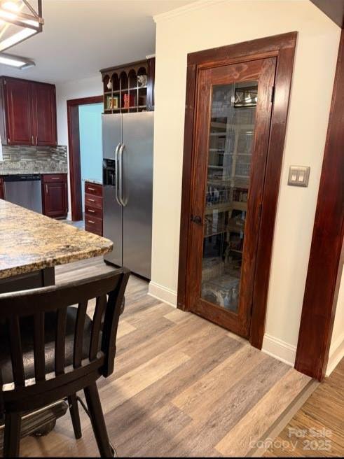 148 Barium Ln, Statesville, NC 28677 - kitchen with stainless steel appliances, reddish brown cabinets, light wood-type flooring, tasteful backsplash, and light stone countertops