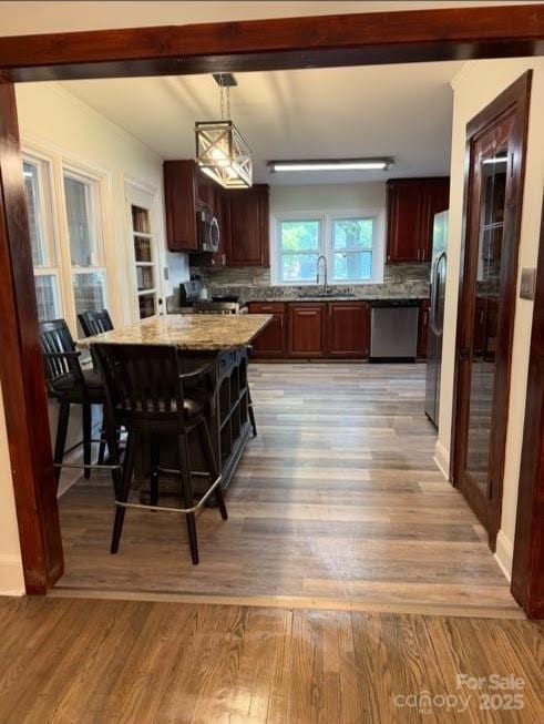 148 Barium Ln, Statesville, NC 28677 - kitchen featuring stainless steel appliances, light wood-type flooring, light stone countertops, tasteful backsplash, and decorative light fixtures
