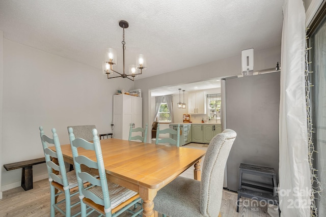 301 Rosemont Ave SE, Concord, NC 28025 - dining area featuring light wood-type flooring, a chandelier, and a textured ceiling