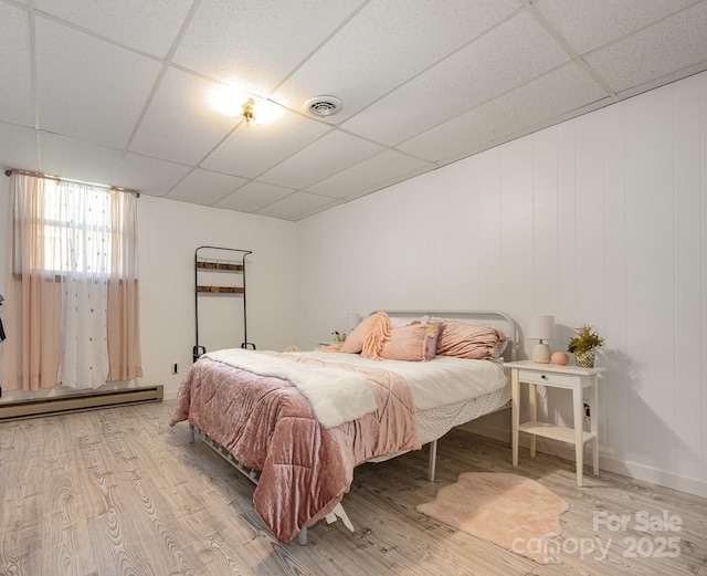 301 Rosemont Ave SE, Concord, NC 28025 - bedroom with a baseboard heating unit, a drop ceiling, and wood finished floors