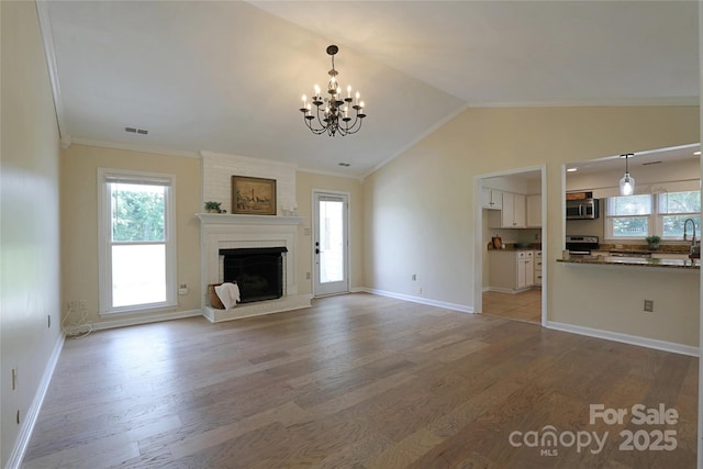 8829 Gelligum Dr, Charlotte, NC 28277 - unfurnished living room featuring light wood finished floors, healthy amount of natural light, ornamental molding, a chandelier, and a fireplace