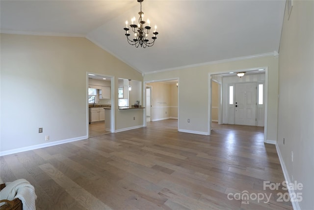 8829 Gelligum Dr, Charlotte, NC 28277 - unfurnished living room featuring a chandelier, healthy amount of natural light, light wood-style flooring, vaulted ceiling, and crown molding