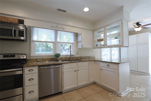 8829 Gelligum Dr, Charlotte, NC 28277 - kitchen featuring stainless steel appliances, light tile patterned floors, dark stone counters, white cabinets, and ornamental molding