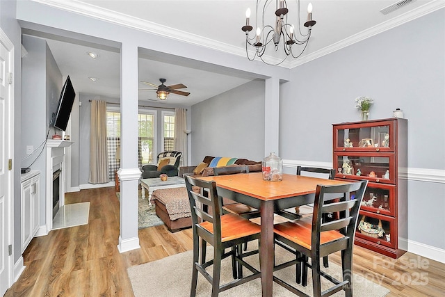 2044 Gable Way Ln, Matthews, NC 28104 - dining area featuring a ceiling fan, light wood-style floors, crown molding, decorative columns, and a chandelier