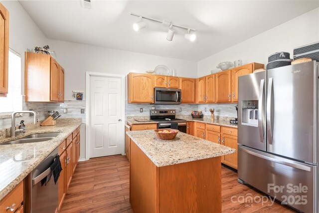 8618 Redding Glen Ave, Charlotte, NC 28216 - kitchen with appliances with stainless steel finishes, wood finished floors, a kitchen island, and tasteful backsplash