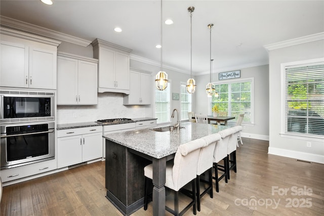 221 N Centurion Ln, Mount Holly, NC 28120 - kitchen with stainless steel appliances, dark wood-type flooring, light stone counters, a kitchen breakfast bar, and backsplash