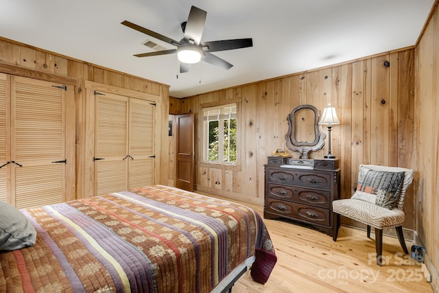 203 Laurel Ln, Little Switzerland, NC 28752 - bedroom with wooden walls, light wood-style floors, multiple closets, and ceiling fan
