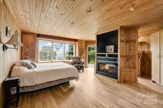 203 Laurel Ln, Little Switzerland, NC 28752 - bedroom with wooden ceiling, multiple windows, wood walls, light wood-style flooring, and a large fireplace