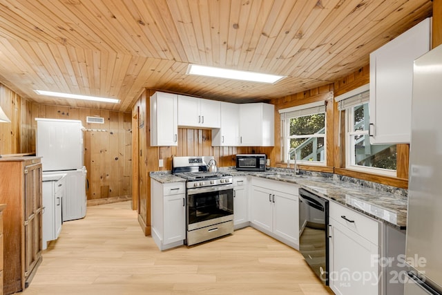 203 Laurel Ln, Little Switzerland, NC 28752 - kitchen featuring wooden ceiling, estacked washer and dryer, light stone counters, black appliances, and wooden walls