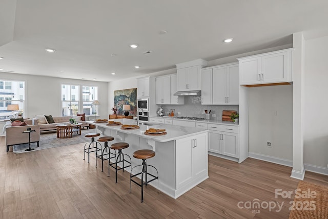 9212 Delancey Ln Unit 63, Concord, NC 28027 - kitchen with light wood finished floors, white cabinets, light countertops, a kitchen bar, and recessed lighting