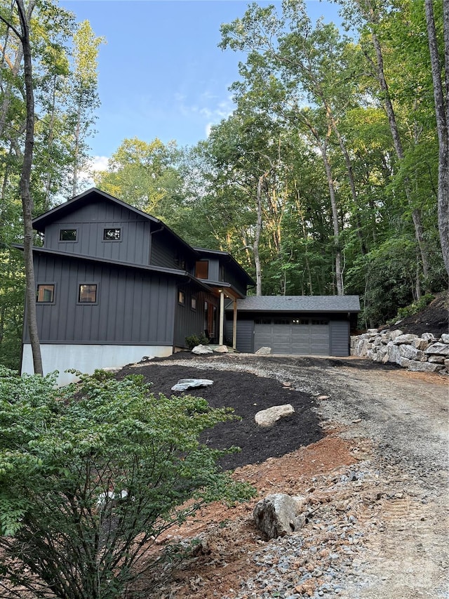 285 Poplar Crest Dr, Pisgah Forest, NC 28768 - view of front of home with board and batten siding, a garage, and dirt driveway