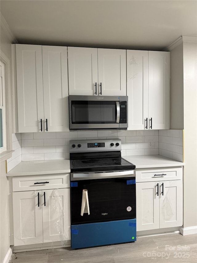 3166 Poplar Tent Rd, Concord, NC 28027 - kitchen featuring stainless steel microwave, range with electric stovetop, light countertops, light wood-style floors, and ornamental molding