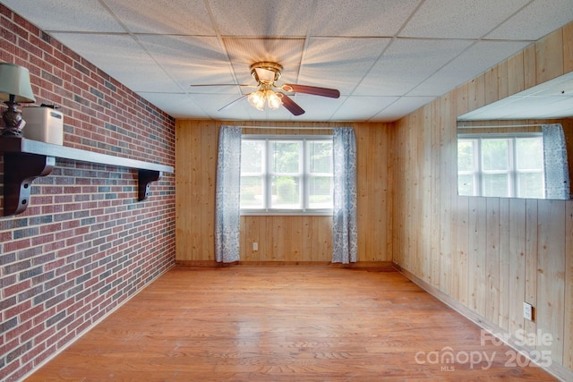 2310 Honeysuckle Pl, Lenoir, NC 28645 - unfurnished room featuring plenty of natural light, wood finished floors, ceiling fan, brick wall, and a drop ceiling