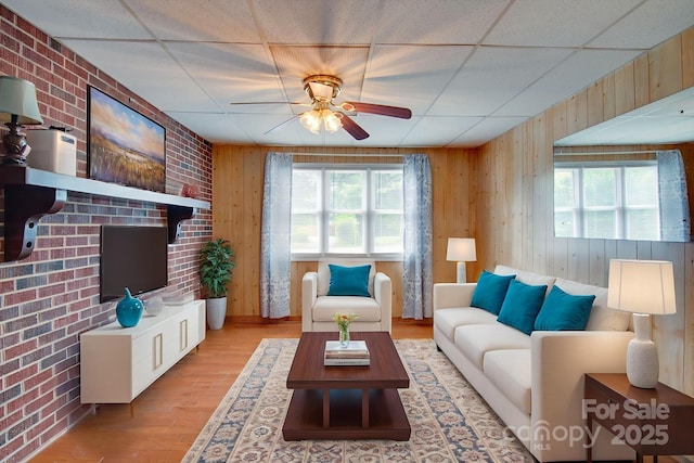 2310 Honeysuckle Pl, Lenoir, NC 28645 - living area with a ceiling fan, wood walls, wood finished floors, brick wall, and a drop ceiling