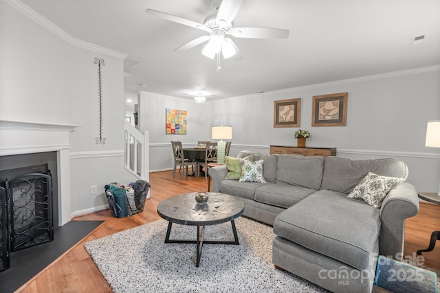 9214 Arbourgate Meadows Ln, Charlotte, NC 28277 - living room featuring wood finished floors, a ceiling fan, ornamental molding, a fireplace with flush hearth, and stairway