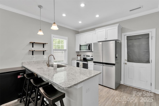 2662 14th St NE, Hickory, NC 28601 - kitchen featuring appliances with stainless steel finishes, a peninsula, light wood finished floors, white cabinetry, and crown molding