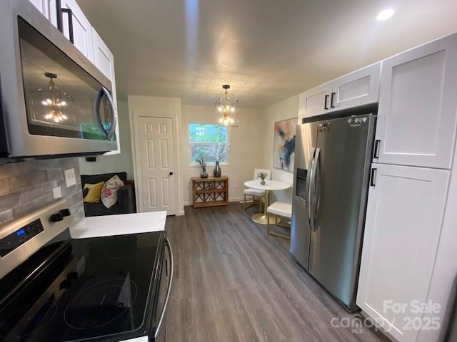 9800 Feldbank Dr, Charlotte, NC 28216 - kitchen with stainless steel appliances, dark wood-type flooring, a chandelier, and white cabinets