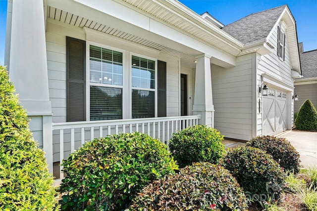 7315 Surprise Ct, Charlotte, NC 28215 - doorway to property featuring roof with shingles, covered porch, concrete driveway, and an attached garage