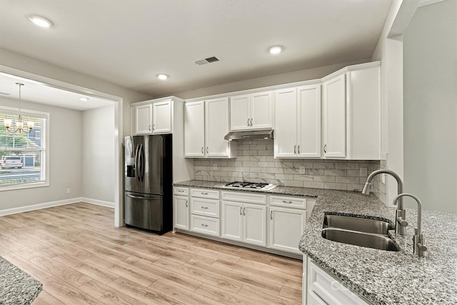 7315 Surprise Ct, Charlotte, NC 28215 - kitchen featuring stainless steel fridge with ice dispenser, under cabinet range hood, white cabinets, light stone counters, and a chandelier