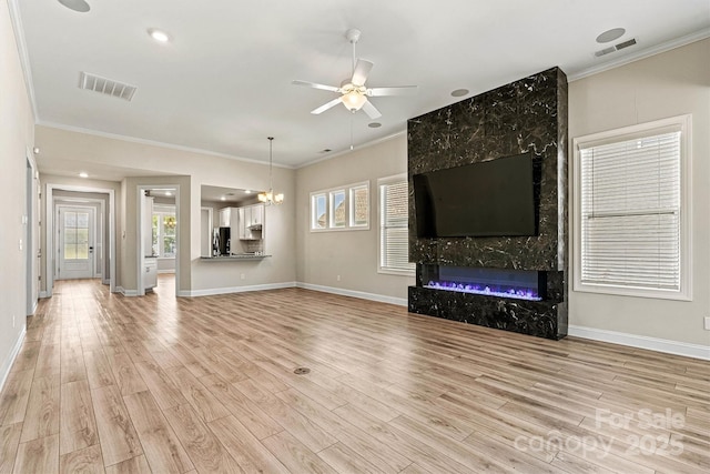 7315 Surprise Ct, Charlotte, NC 28215 - unfurnished living room featuring a ceiling fan, light wood finished floors, ornamental molding, a fireplace, and a chandelier