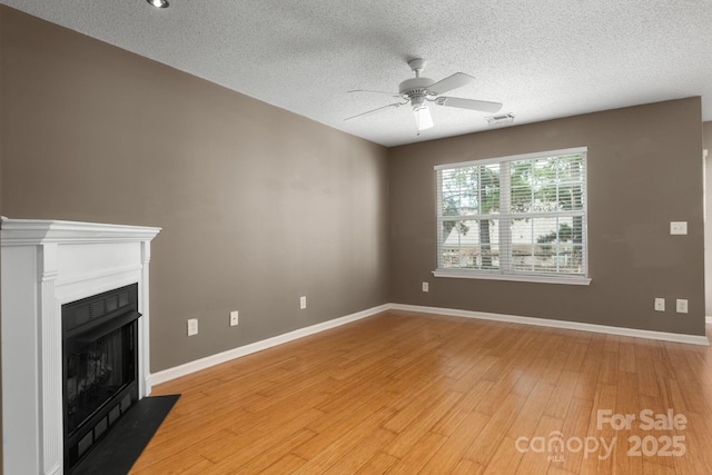 10613 Prairie Ridge Ln, Charlotte, NC 28213 - unfurnished living room featuring ceiling fan, light wood-type flooring, a textured ceiling, and a fireplace with flush hearth