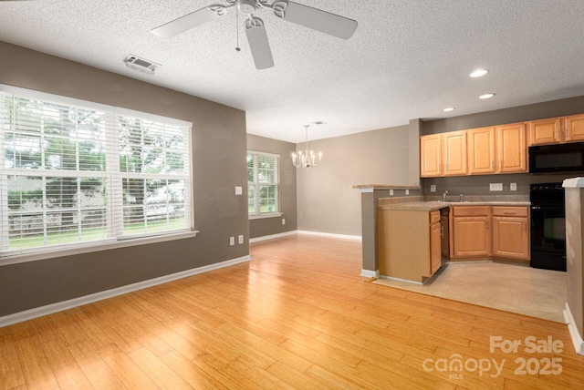 10613 Prairie Ridge Ln, Charlotte, NC 28213 - kitchen with black appliances, a chandelier, a textured ceiling, light brown cabinetry, and a peninsula
