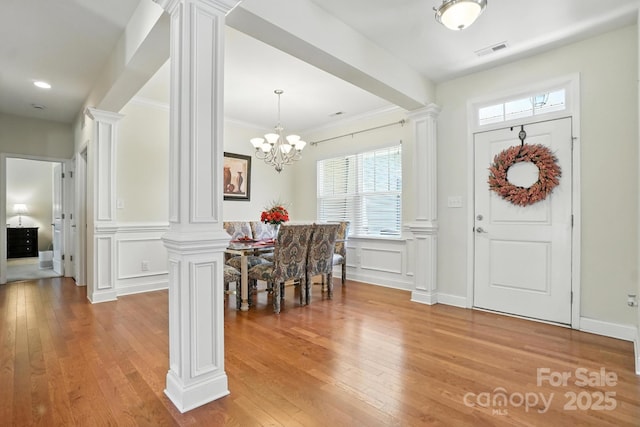 8275 Normandy Rd, Denver, NC 28037 - entrance foyer with ornate columns, a decorative wall, light wood finished floors, a chandelier, and a wainscoted wall