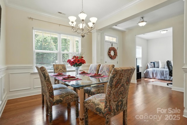8275 Normandy Rd, Denver, NC 28037 - dining area featuring a chandelier, hardwood / wood-style floors, wainscoting, ornamental molding, and ornate columns