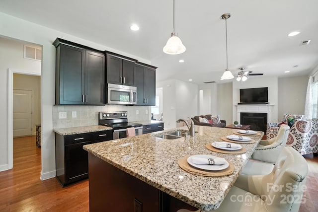8275 Normandy Rd, Denver, NC 28037 - kitchen with appliances with stainless steel finishes, open floor plan, light stone counters, wood finished floors, and recessed lighting