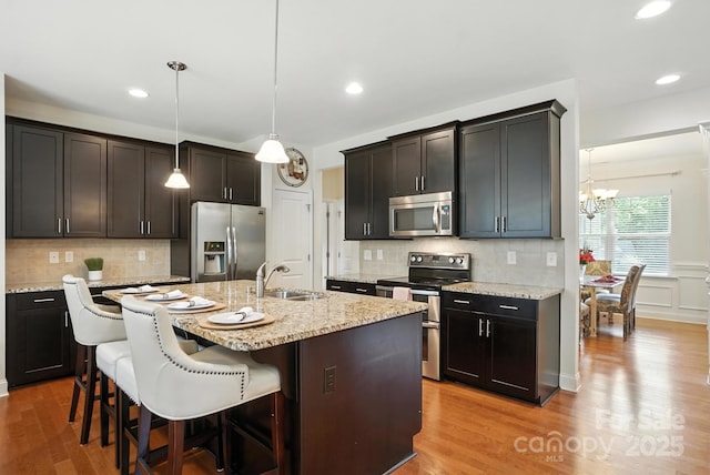 8275 Normandy Rd, Denver, NC 28037 - kitchen featuring appliances with stainless steel finishes, a chandelier, a kitchen bar, wood finished floors, and backsplash