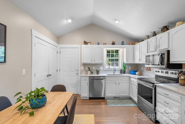 12 Buckshot Ridge Dr, Asheville, NC 28804 - kitchen featuring appliances with stainless steel finishes, vaulted ceiling, white cabinetry, light countertops, and wood finished floors
