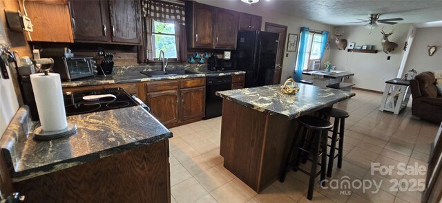 414 Pine Cove Rd, Old Fort, NC 28762 - kitchen featuring black appliances, a breakfast bar area, a kitchen island, a ceiling fan, and dark stone countertops