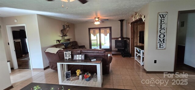 414 Pine Cove Rd, Old Fort, NC 28762 - living room featuring a ceiling fan, a wood stove, light tile patterned floors, and a textured ceiling