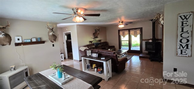 414 Pine Cove Rd, Old Fort, NC 28762 - living room featuring light tile patterned floors, a ceiling fan, a wood stove, and a textured ceiling
