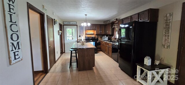 414 Pine Cove Rd, Old Fort, NC 28762 - kitchen featuring black appliances, a breakfast bar area, a kitchen island, dark brown cabinets, and a chandelier