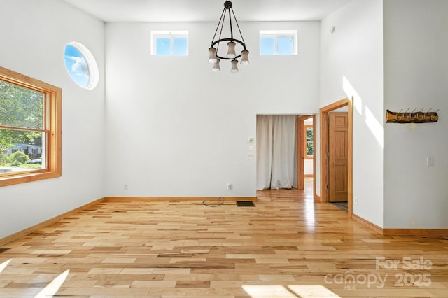109 Azalea Ave, Swannanoa, NC 28778 - unfurnished room with a high ceiling, a chandelier, and light wood-style flooring