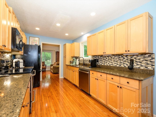 1047 Honeybee Trl, Fort Mill, SC 29715 - kitchen with appliances with stainless steel finishes, light brown cabinetry, backsplash, light wood-style flooring, and dark stone countertops