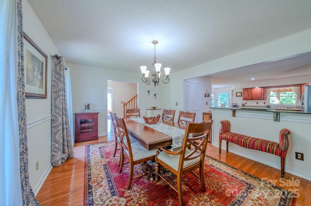 74 Challedon Dr, Candler, NC 28715 - dining area featuring light wood finished floors, a chandelier, a textured ceiling, and stairs