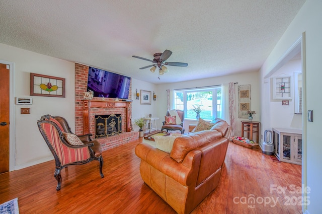 74 Challedon Dr, Candler, NC 28715 - living room featuring a textured ceiling, ceiling fan, wood finished floors, and a brick fireplace