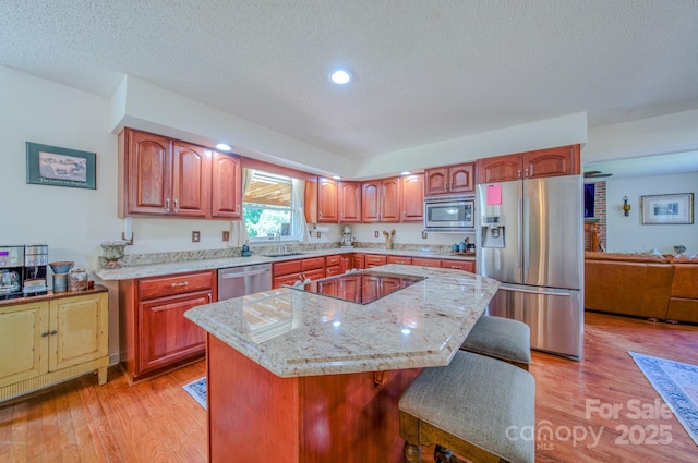 74 Challedon Dr, Candler, NC 28715 - kitchen with appliances with stainless steel finishes, light wood-type flooring, a kitchen breakfast bar, a kitchen island, and a textured ceiling
